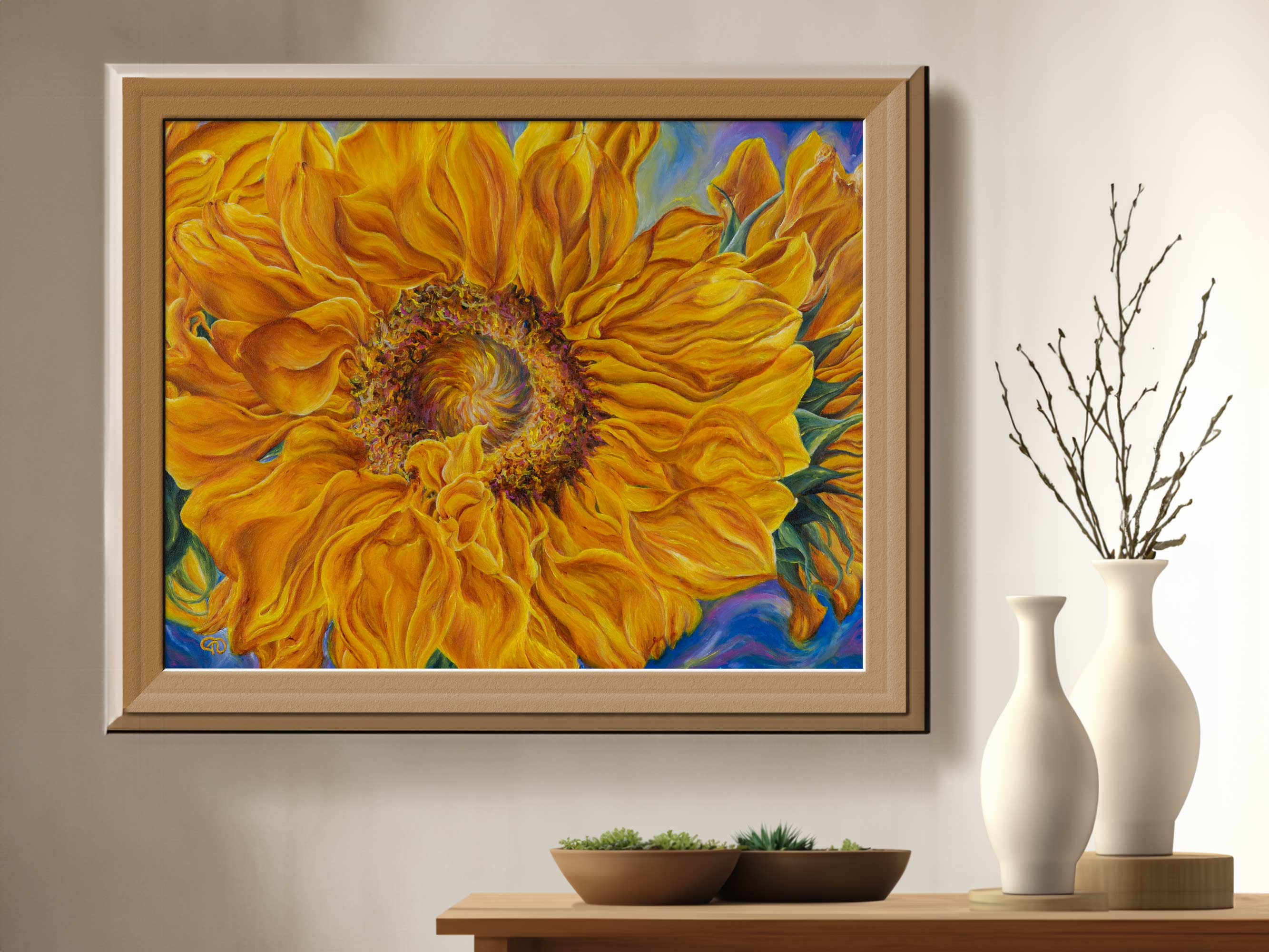 Reproduction print of a sunflower with large petals extending from the swirling center pictured in a light brown frame positioned on a wall. Two ceramic vases and potted plants decorate the shelf in the foreground.